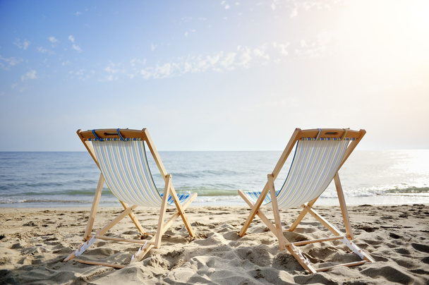 duas cadeiras na praia de areia ao pôr do sol à procura do mar - conceito de relaxamento
 - Foto, Imagem