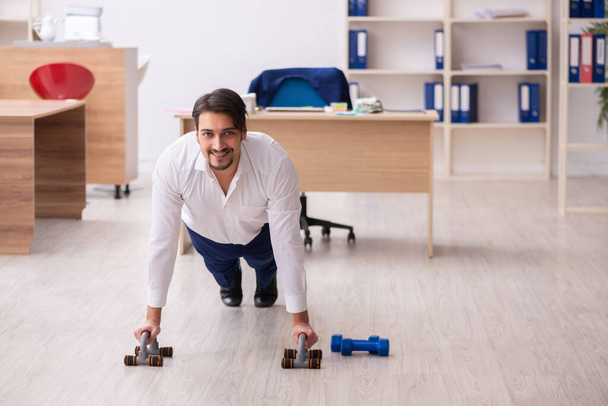 Young male employee doing sport exercises during break - Photo, image