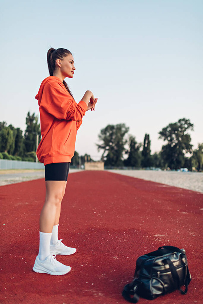 Sabahın erken saatlerinde spor sahasında ısınma egzersizleri yapan genç bir kadın. - Fotoğraf, Görsel