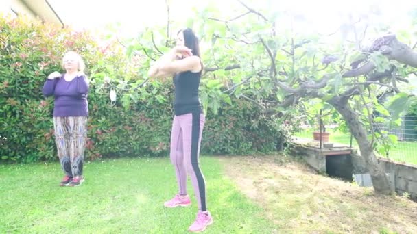 Cuatro mujeres que tienen fitness al aire libre con mascarilla colgando de los árboles - Imágenes, Vídeo