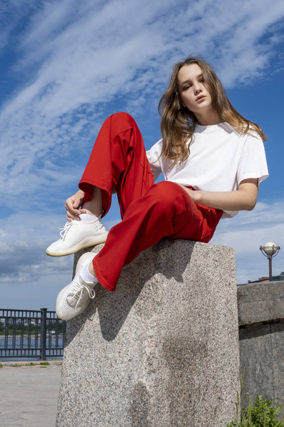 teenage girl sits on the concrete fence of the Angara embankment - Fotoğraf, Görsel