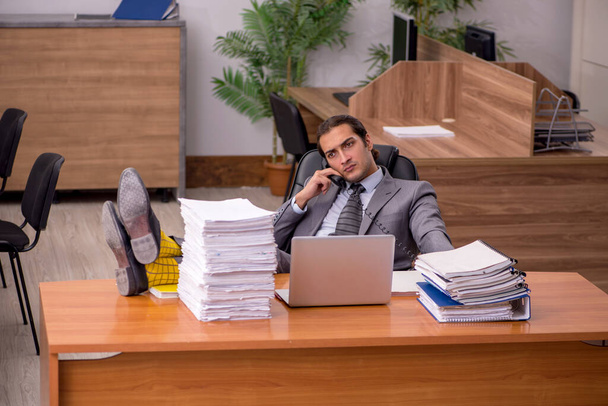 Nuori miespuolinen työntekijä ja liikaa työtä toimistossa - Valokuva, kuva