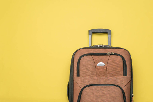 A convenient travel suitcase on a yellow background. Equipment for transporting things on trips. Flat lay. - Foto, Imagen