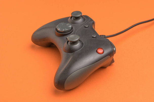 オレンジの背景にコンピュータゲームのためのリモートコントロール。コンピュータゲームをプレイするための装置. - 写真・画像