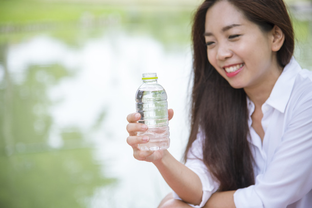 Счастье Красивые азиатские китайские женщины держат бутылку минеральной воды. Молодая женщина пьет воду из бутылки в зеленом саду парка. Азиатская женщина бутылка питьевой воды здоровый человек счастлив и улыбается - Фото, изображение