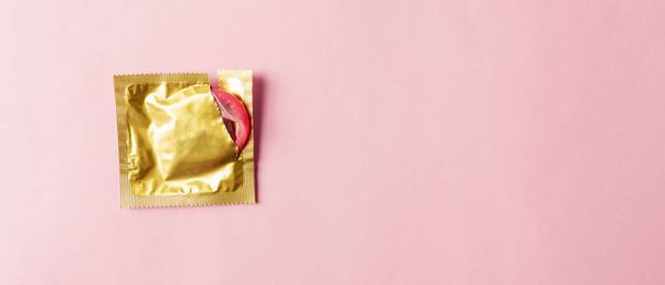 World sexual health or Aids day, Top view flat lay condom in wrapper pack is tear open, studio shot isolated on a pink background, Safe sex and reproductive health concept - Фото, изображение