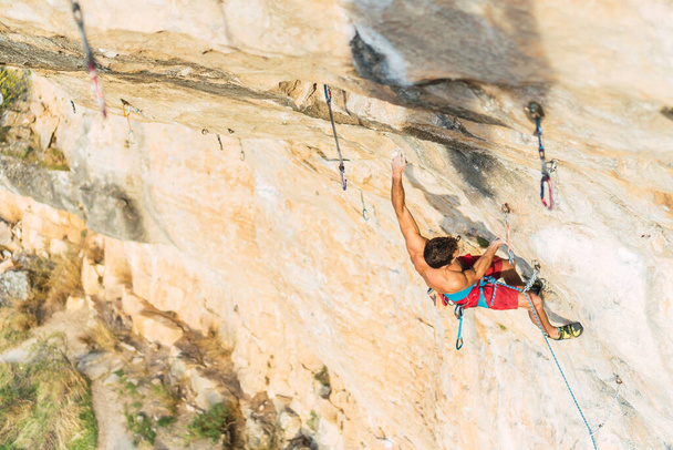Hombre escalador escalador escalada roca formación en día soleado. - Foto, imagen