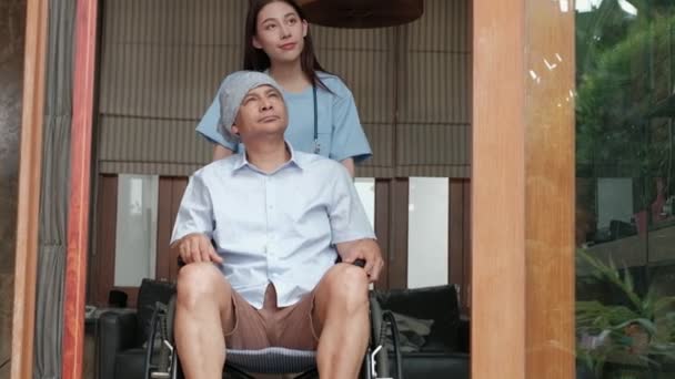 Pacientes de edad avanzada con cáncer en sillas de ruedas reciben tratamiento de rehabilitación en el hogar privado, tratamientos médicos médicos femeninos asiáticos al hablar para curar la soledad y alentarlos con una sonrisa.  - Metraje, vídeo
