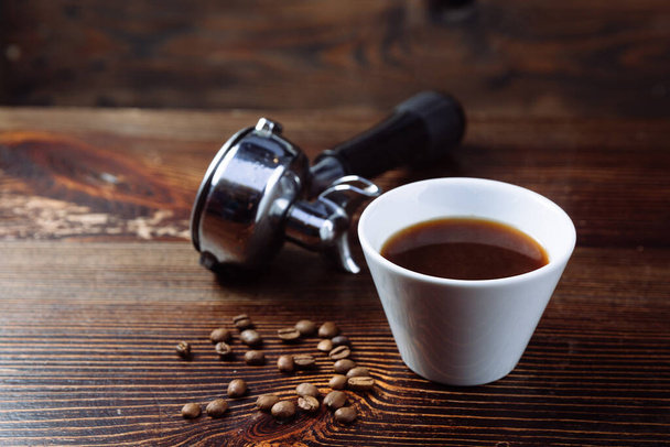 Ένα φλιτζάνι μαύρο καφέ και φίλτρο κάτοχος του espresso. - Φωτογραφία, εικόνα