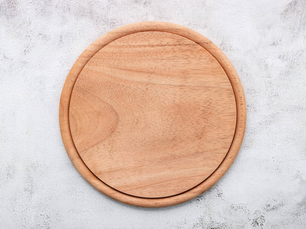 Пустая деревянная тарелка для пиццы установлена на белом бетоне. Доска на белом бетонном фоне плоская и пространство для копирования. - Фото, изображение