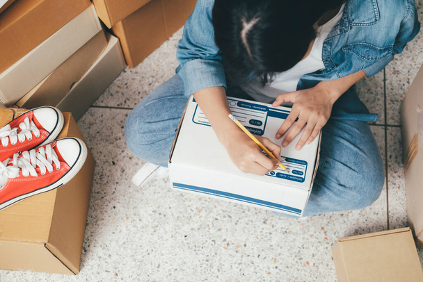 Closeup hand of young woman writing address on parcel box for delivery order to customer, shipping and logistic, merchant online and seller, business owner or sme, online shopping. - Photo, Image