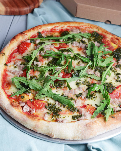 Traditional italian seafood pizza with tomatoes and fresh arugula. Italian cuisine concept. Close up on pizza. Served over light wooden background. - Photo, Image
