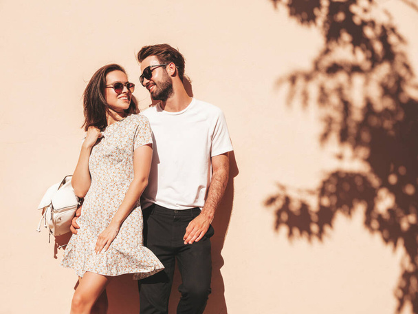 Portrait of smiling beautiful woman and her handsome boyfriend. Woman in casual summer clothes. Happy cheerful family. Female having fun. Couple posing in the street near wall in sunglasses - Foto, Bild