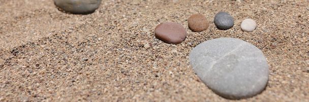 Los pies son de piedras en la arena de la playa. - Foto, imagen