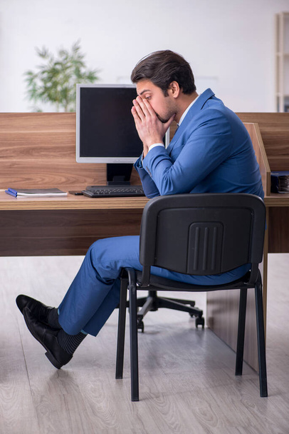 Giovane dipendente maschile seduto sul posto di lavoro - Foto, immagini