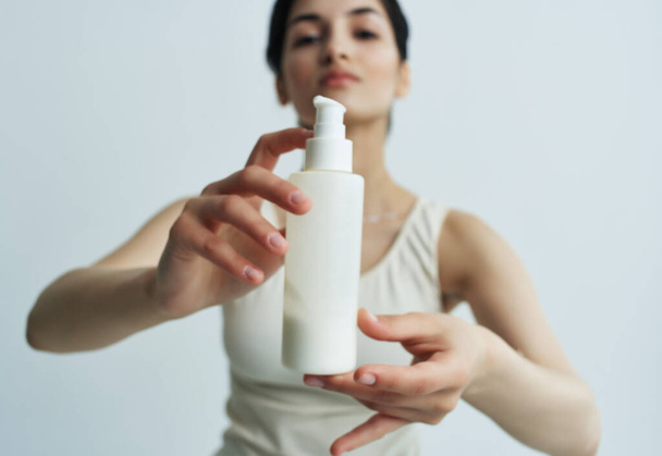 Frau mit einem Glas Lotion in den Händen in einem weißen T-Shirt Hautpflege-Wellness-Behandlungen - Foto, Bild