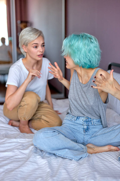 Two female friends or lesbians sitting on bed, arguing with each other. Friendship, quarrel - Fotoğraf, Görsel
