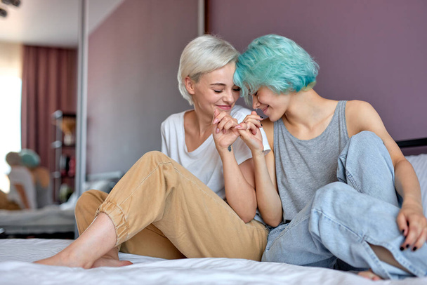 Together forever, young lovely lesbian couple keeping fingers together, sitting on bed - Fotoğraf, Görsel