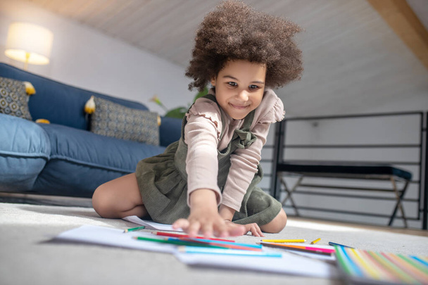 Little girl choosing colored pencil on floor - Foto, Bild