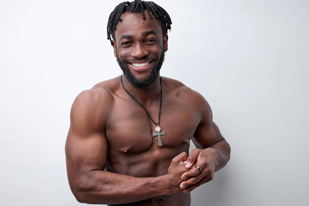 Happy young man with beautiful torso showing arms biceps, isolated on white background - Φωτογραφία, εικόνα