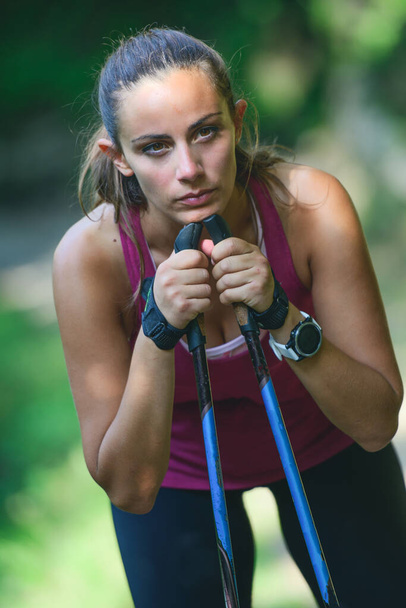Young sporty woman with Nordic walking poles is resting - Φωτογραφία, εικόνα
