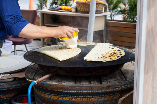 tradiční turecká kuchyně, pouliční jídlo: palačinka. místní žena vaří palačinky na kovovém plechu, do kterého dává sýr, špenát nebo brambory. Selektivní palačinky zaměření. - Fotografie, Obrázek