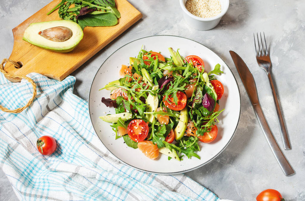Salmon salad with green leaves, avocado and cherry tomato on concrete background - Photo, Image