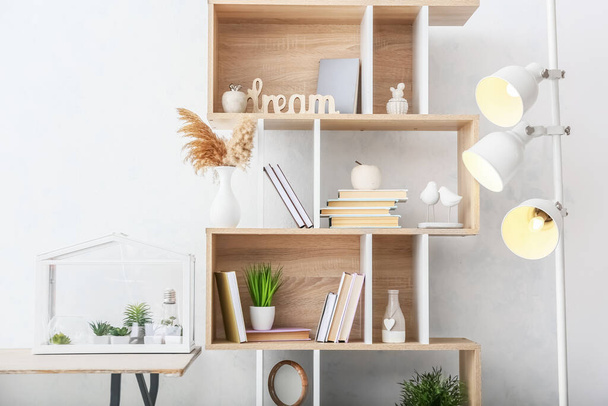 Stylish shelf unit with books and decor near light wall - Фото, зображення