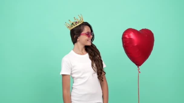 gelukkig tiener meisje in zonnebril en koningin kroon voelde zich verward na hart ballon vloog, plotselinge. - Video