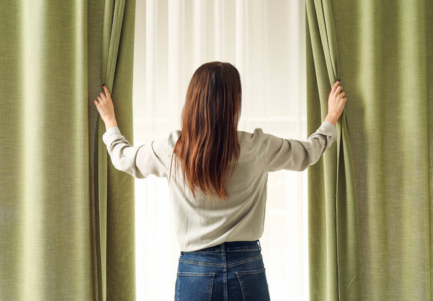 Young woman opening light curtains at home - Foto, Bild