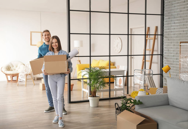 Jeune couple avec des boîtes en carton dans leur nouvelle maison le jour du déménagement - Photo, image