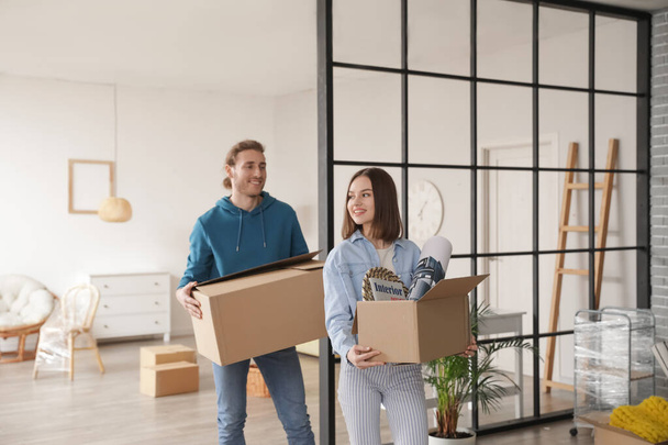 Young couple with cardboard boxes in their new house on moving day - Photo, Image