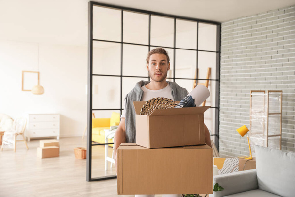 Молодой человек с коробками в комнате в день переезда - Фото, изображение
