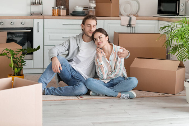 Young couple with cardboard boxes in their new house on moving day - Foto, afbeelding