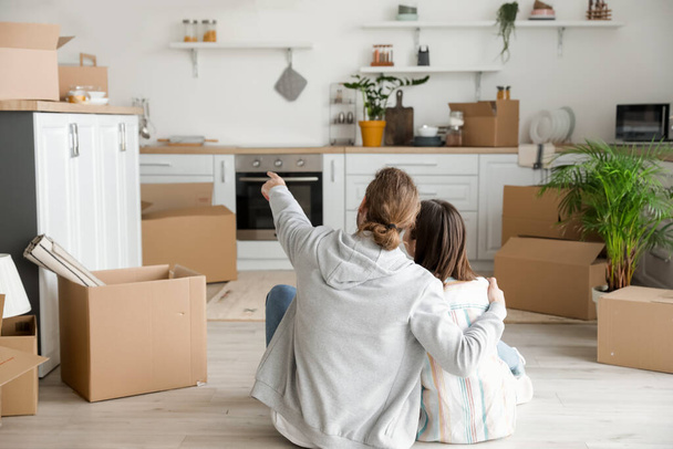 Young couple with cardboard boxes in their new house on moving day - Foto, afbeelding