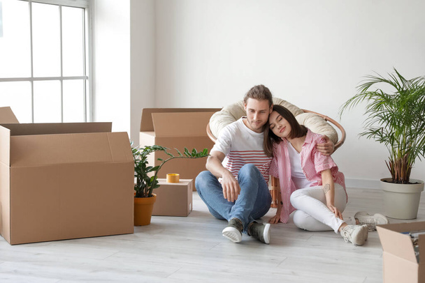 Young couple with cardboard boxes in their new house on moving day - Foto, imagen