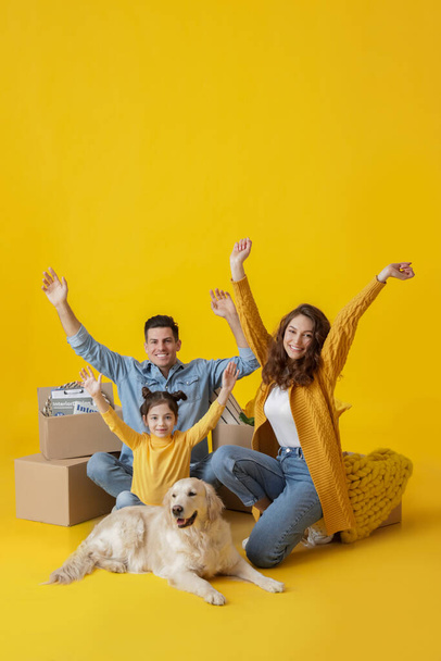Happy family with dog and belongings on color background - Fotografie, Obrázek