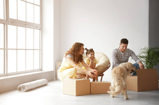 Happy family with dog and moving boxes in their new house - Fotografie, Obrázek