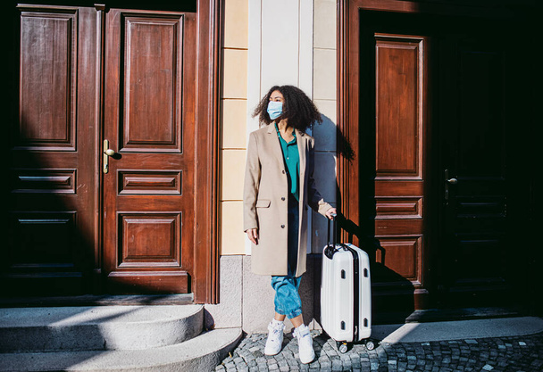 Young woman tourist with luggage standing on streets in old town, coronavirus concept. - Fotografie, Obrázek