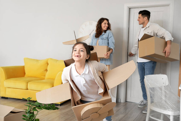 Little girl with cardboard airplane playing in room on moving day - Foto, afbeelding