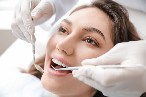 Jonge vrouw bezoeken tandarts in kliniek, closeup - Foto, afbeelding