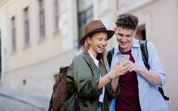 Young couple travelers with smartphone in city on holiday, sightseeing. - Zdjęcie, obraz