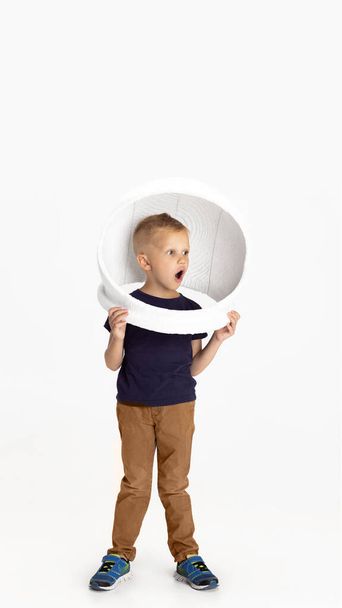 One preschool boy standing isolated on white studio background. Copyspace for ad. Childhood, education, emotion concept. Little astronaut - 写真・画像