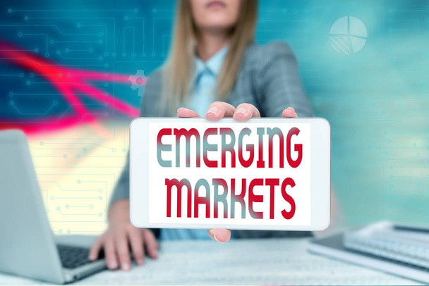 Sign displaying Emerging Markets. Concept meaning nations that are investing in more productive capacity Business Woman Sitting In Office Holding Mobile Displaying Futuristic Ideas. - Photo, Image