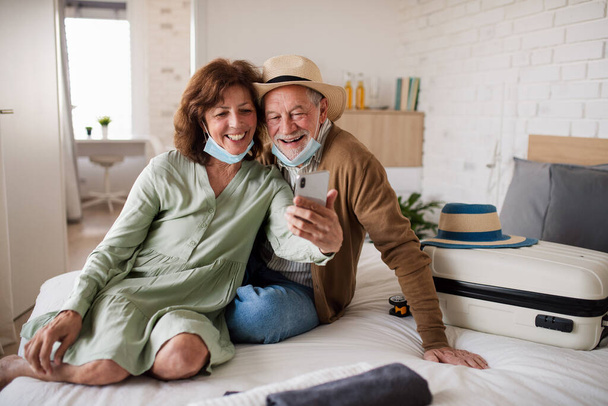 Senior couple taking selfie in hotel room, coronavirus, holiday and new normal concept. - Фото, зображення