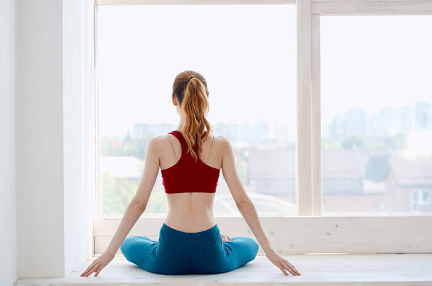 Kadın pencerenin yanında yoga egzersizi yapıyor. - Fotoğraf, Görsel