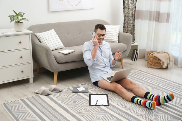 Businessman in shirt and underwear talking on phone during video call at home - Foto, Bild