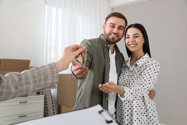 Immobilienmakler übergibt Schlüssel an glückliches junges Paar in neuem Haus - Foto, Bild