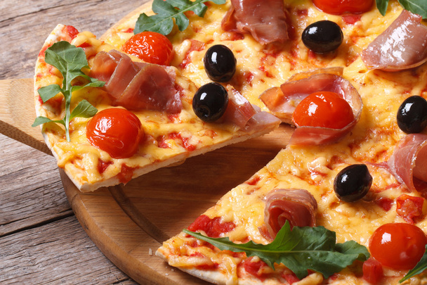 кусок пиццы с ветчиной, помидорами, черными оливками и рукколой
 - Фото, изображение
