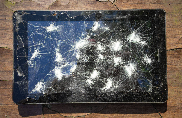Ahşap bir masada kırık ekranlı siyah elektronik tablet, ofis ekipmanları onarımı - Fotoğraf, Görsel